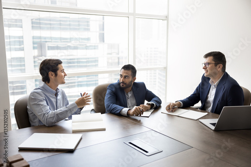Group of diverse businessmen sitting at desk listening team leader make speech. Hispanic boss share solutions, planning cooperation with clients, consulting, lead conversation during formal meeting