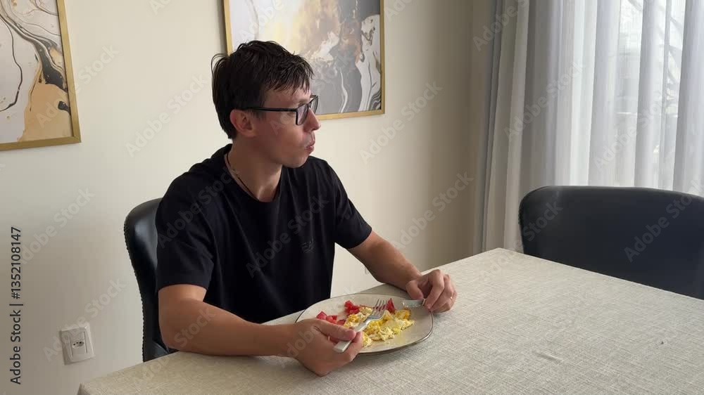 homem comendo ovos e tomate no almoço 