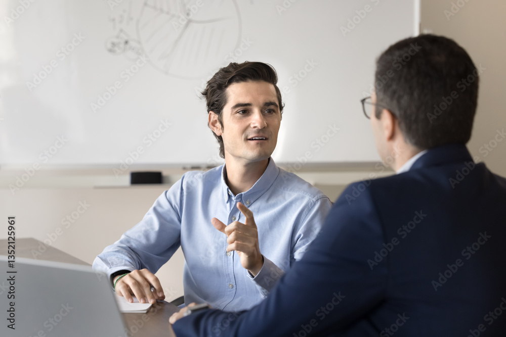 Professional Hispanic businessman consulting client in office. Two employees working on joint task met in office, exchanging point, opinions and solutions, engaged in teamwork, business communication