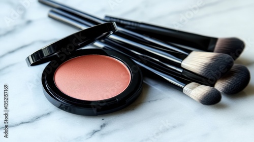 A round peach blush compact with a matte finish placed next to a set of high-end makeup brushes.
