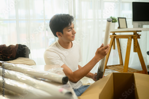 Fotografie Young man unpacking furniture part, ready to assemble furniture in his living ro