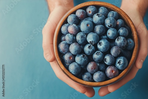 Fresh Blueberries Arranged in a Wooden Bowl on a Blue Background