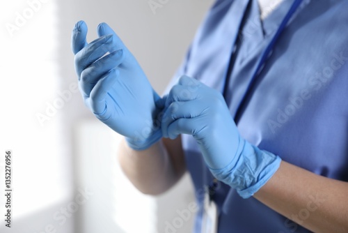Medical worker putting on gloves in hospital, closeup