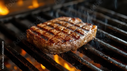 A perfectly grilled, round piece of juicy beef sizzling on the grill, with a golden-brown crust and tender interior visible.