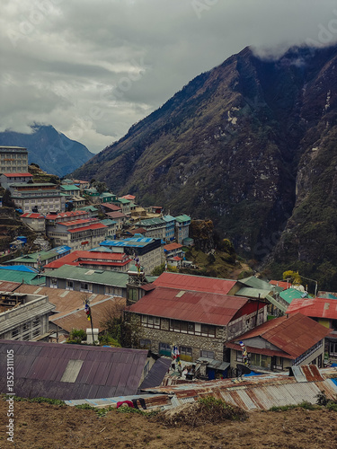 Mountain village with colorful rooftops on a steep slope under cloudy sky