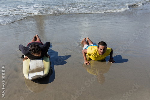 Photography latin surf instructor and two men beginner surfers try to stand up on surfboard