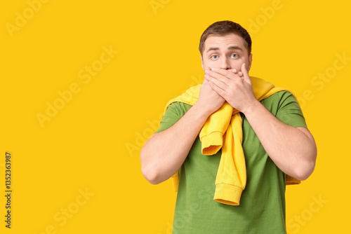 Shocked young man on yellow...
