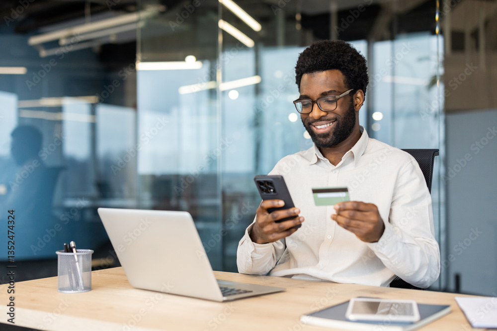 custom made wallpaper toronto digitalSmiling man wearing glasses is shopping online using his credit card and phone at his desk in his office.