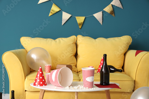 Party hat with popcorn and bottle on table in messy living room after Birthda...