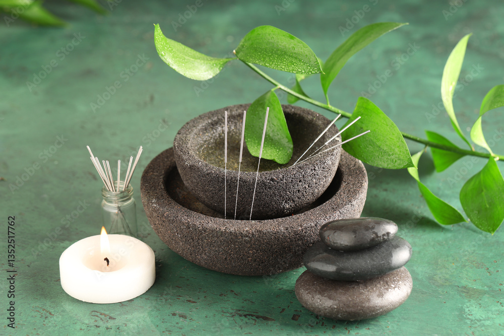 Obraz premium Acupuncture needles, candle and spa stones on green background
