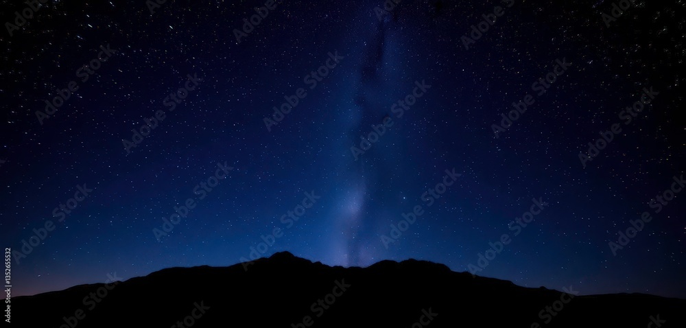 Fototapeta premium Vast night sky ablaze with stars above a silhouetted mountain range, travel, outdoors