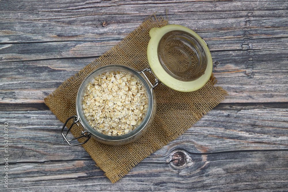 Oat flakes uncooked in a brown bowl on wooden table. Healthy food for breakfast