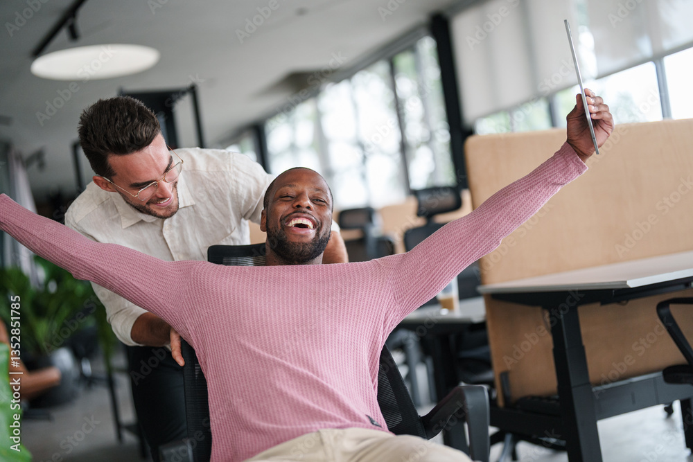 Obraz premium Two Male Colleagues Share a Joyful Moment in a Bright Office Space