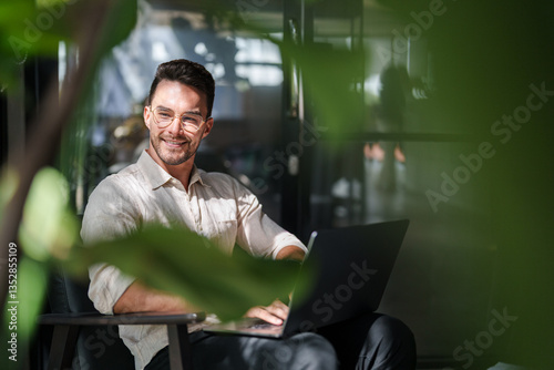 Fotografi Young Male Professional With Glasses Working On Laptop In Contemporary Office Su