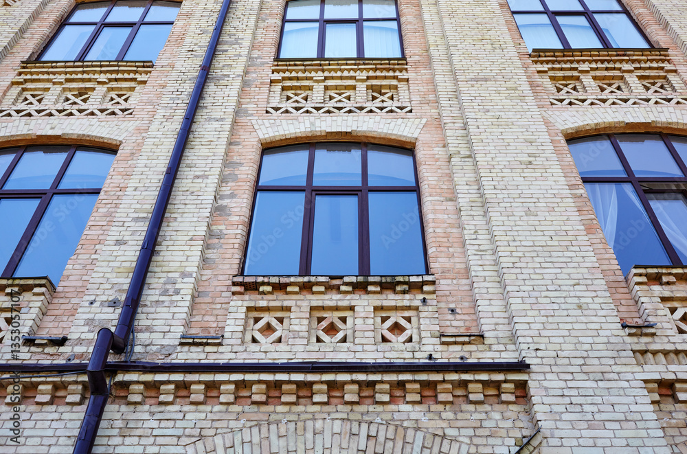 Obraz premium Brick classic facade of 19 century building with large windows. Old building with downspout in Kyiv, Ukraine