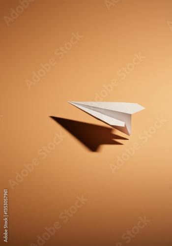 Minimalist Origami Paper Airplane in Flight: Creative Shadow Play and Design Elements in Warm Tones