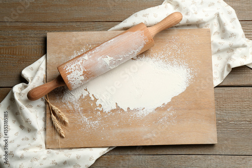 Rolling pin, board, flour and spikes on wooden table, top view