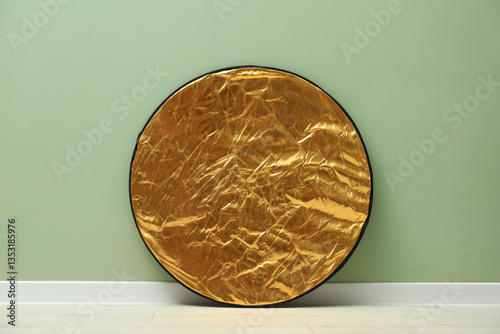 One light reflector near green wall indoors. Photo studio equipment