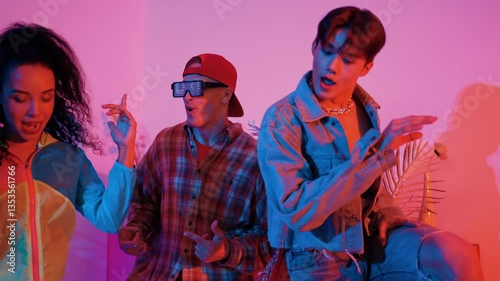 Professional break dancer perform and practicing street dancing with neon light. Happy team moving to hip hop music while wearing casual cloth while caucasian man show energetic movement. Regalement.