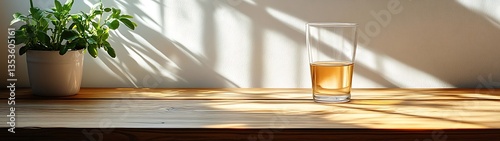 A glass of liquid next to a potted plant on a wooden table
