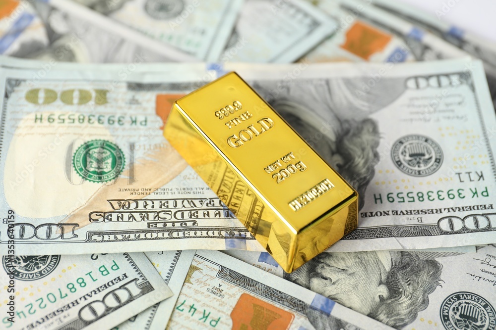 Shiny gold bar on dollar banknotes, closeup Shiny gold bar on dollar banknotes, closeup
