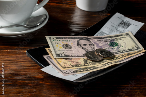 American money in a tip tray when paying a bill after eating at a restaurant, closeup. Paying for your bill tab at a restaurant cafe with cash money