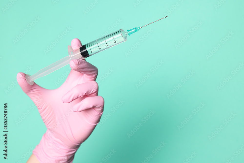 Doctor holding syringe with medication on turquoise background, closeup. Space for text Doctor holding syringe with medication on turquoise background, closeup. Space for text