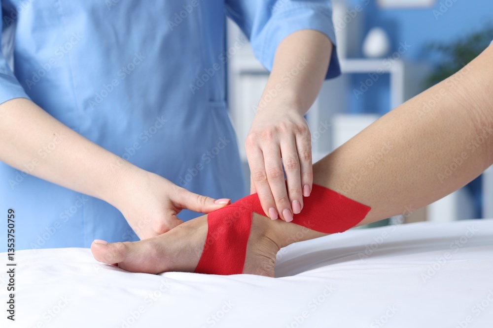 Fototapeta premium Doctor applying kinesio tapes to patient's foot in hospital, closeup