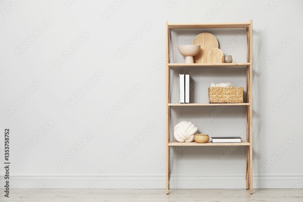 Wooden shelving unit with different home decor near light grey wall indoors. Space for text Wooden shelving unit with different home decor near light grey wall indoors. Space for text