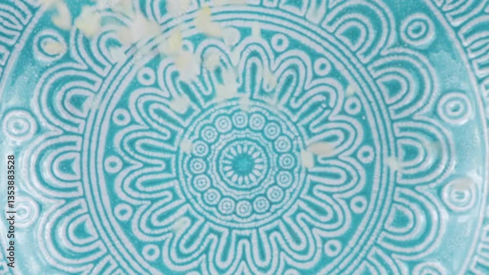 Round grain rice is poured into a ceramic blue bowl against a wooden oak board. Top view. Slow motion.