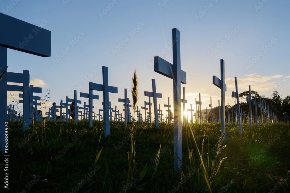 White crosses on the green grass at Anzac Day commemoration. Unrecognizable people paying respect. Auckland. New Zealand.