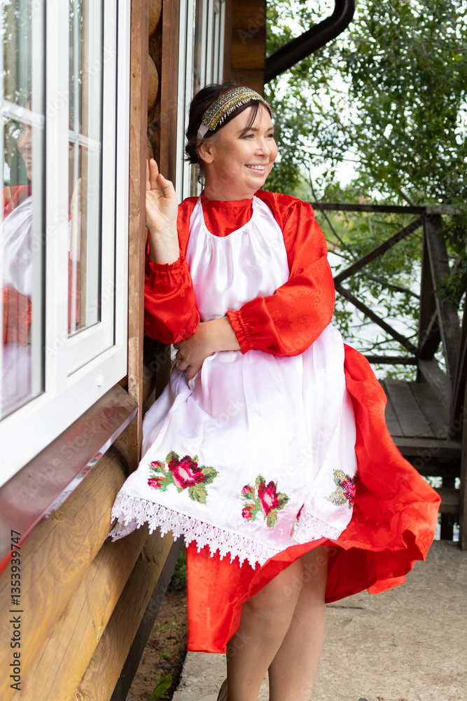 Obraz premium a woman in a national Udmurt costume. small nations.A woman in a national costume stands at the cottage, summer