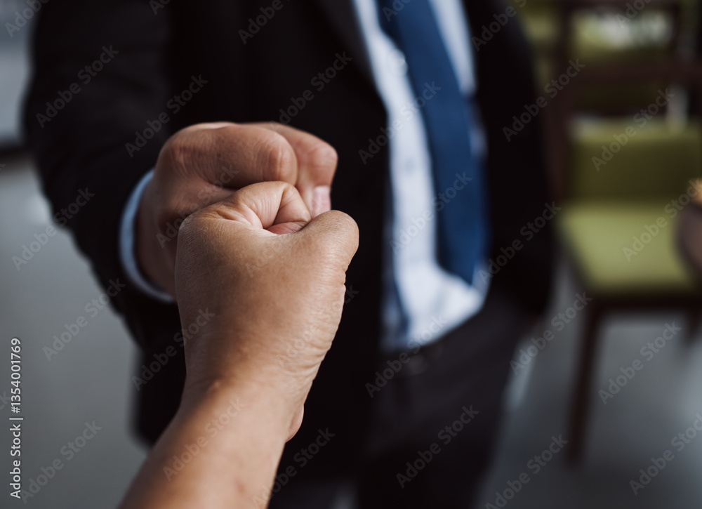 Fototapeta premium Close-up of two business professionals giving a fist bump, symbolizing teamwork, success, and motivation. Perfect for concepts of partnership, collaboration, and corporate culture.