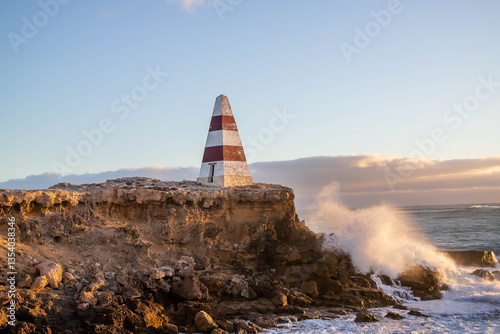 Historic Robe Obelisk stands tall on the rugged coastline of South Australia, surrounded by waves, cliffs, and deep blue sea