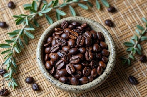 Aromatic coffee beans in rustic bowl on woven mat with green leaves