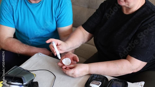 an elderly couple, a husband and wife, engaged in a thoughtful moment as they measure blood sugar levels using a home monitoring device.
