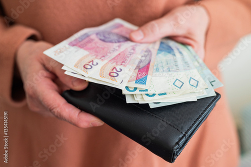 pensioner woman holding in her hands money bills zloty pension and pennies for payment