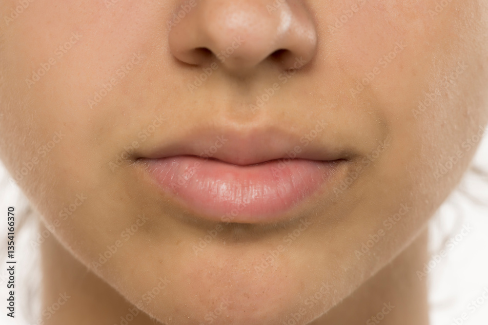 Obraz premium Close-up of natural, makeup-free lips and skin. Detailed view showing texture, subtle freckles, and soft lip color. Skincare and beauty concept