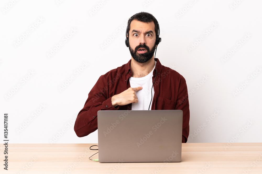 Telemarketer caucasian man working with a headset and with laptop pointing to oneself. Telemarketer caucasian man working with a headset and with laptop pointing to oneself.