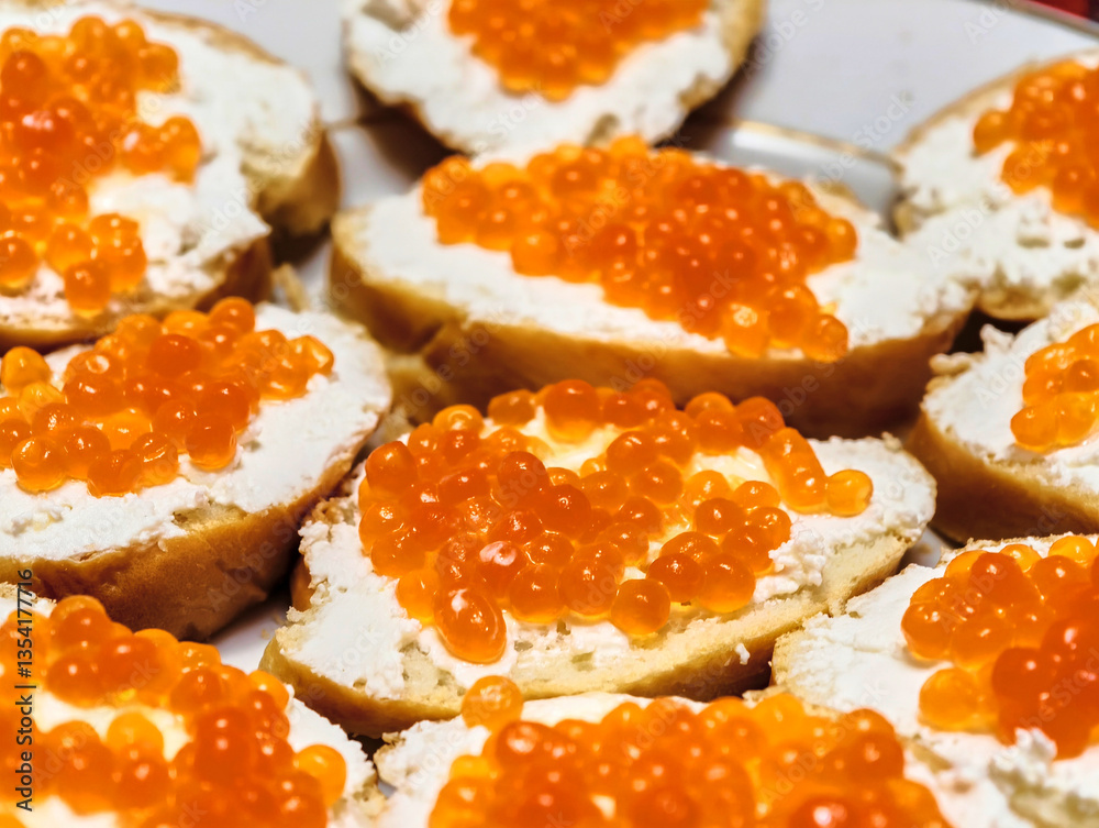 Exquisite appetizers showcasing fresh cream cheese and vibrant orange caviar on toasted bread served at a festive gathering