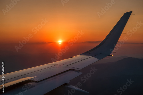 Obraz na płótnie Beautiful view from airplane window on colorful orange sky with evening light and wing of plane w salonie