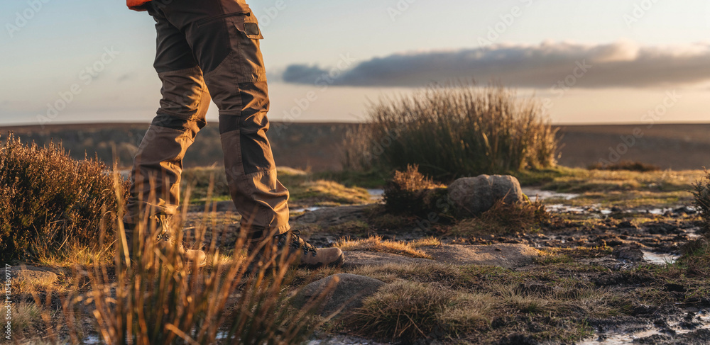 Hiker enjoying stunning sunset view over rugged terrain in the countryside during tranquil evening walk in nature Hiker enjoying stunning sunset view over rugged terrain in the countryside during tranquil evening walk in nature