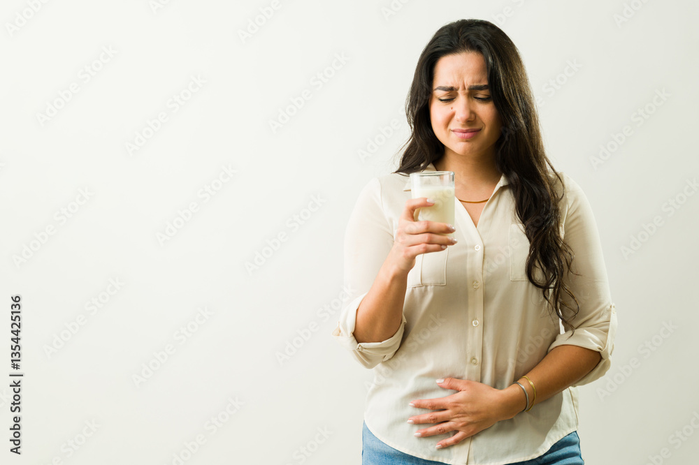 Young woman holding glass of milk and suffering stomach ache because of lactose intolerance, having bad symptoms and feeling sick Young woman holding glass of milk and suffering stomach ache because of lactose intolerance, having bad symptoms and feeling sick