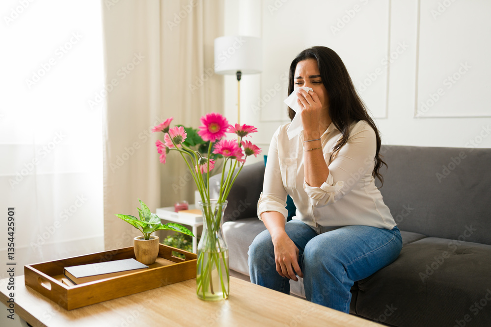 Allergic latin woman dabbing runny nose with tissue while seated on living room sofa near blooming flowers Allergic latin woman dabbing runny nose with tissue while seated on living room sofa near blooming flowers