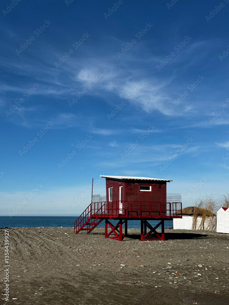 Red Lifeguard Hut on Sandy Beach Under Blue Sky