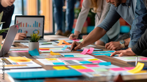 Collaboration in the office with colleagues brainstorming ideas, reviewing colorful sticky notes and documents on a table, photo