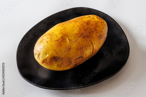 Fresh organic golden potatoes on a black plate