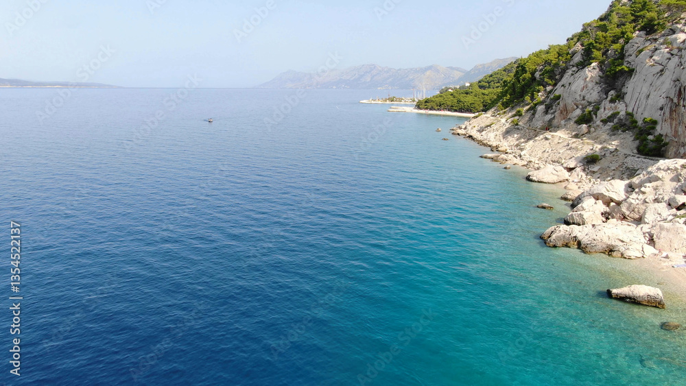 Obraz premium Scenic aerial view of a breathtaking coastal landscape with lush green mountains meeting the turquoise sea. A perfect destination for nature lovers and travel enthusiasts.