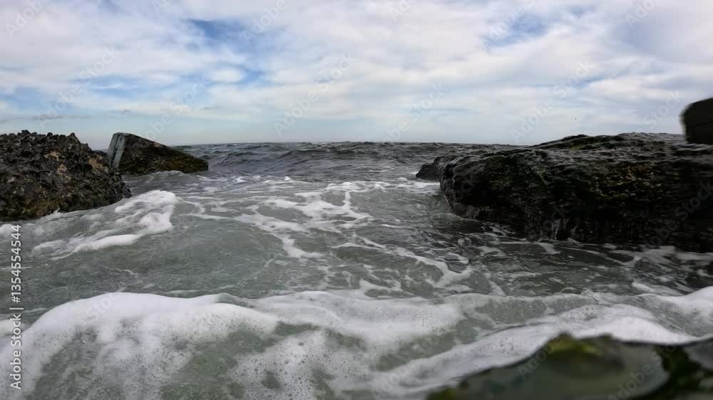 Waves with air bubbles in the water flood the video camera and stones overgrown with mussels and algae, Storm in the Black Sea Waves with air bubbles in the water flood the video camera and stones overgrown with mussels and algae, Storm in the Black Sea