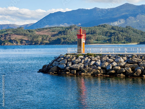 Lighthouse reflected in the sea in the harbor of Lastres. Llastres, Colunga, Asturias, Spain, Europe